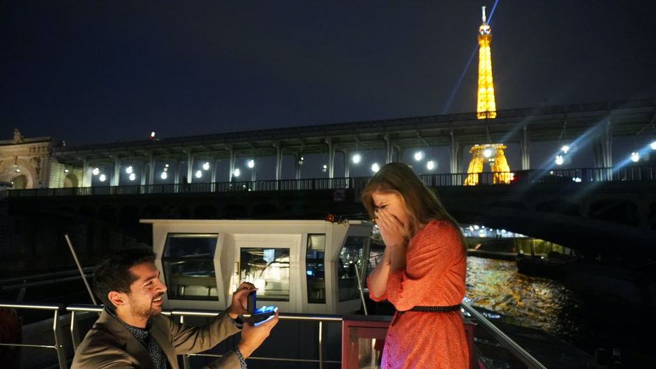Sunny proposing to Tanya on top of a boat in Paris, with the Eiffel Tower lighting up in the background